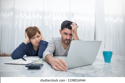 Worried Couple Paying Bills Online Via Laptop In Living Room. Young Man Woman With Computer And Checkbook, Worry About Expense Bills, Hands Holding Head. Stressful Financial Problem Technology Concept