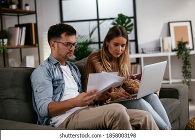 Worried Couple Paying Their Bills Online With Laptop At Home In The Living Room. Couple Having Financial Problems.	