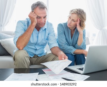 Worried Couple Using Their Laptop To Pay Their Bills At Home In The Living Room