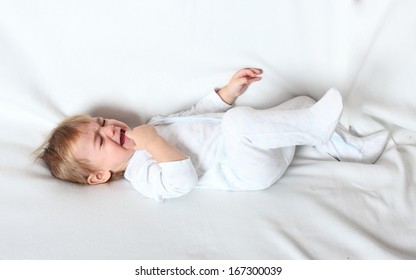 Worried Crying Child Lying On A Bed.