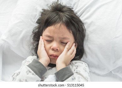 Worried Crying Child Lying On A Bed.