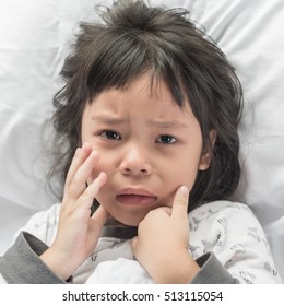 Worried Crying Child Lying On A Bed.