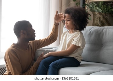 Worried Dad Father Check Temperature Touch Forehead Of Biracial Unhealthy Schoolgirl Daughter Sitting On Sofa At Home. Ill Sick Kid Girl, Parenting Support, Care Love, Treatment And Healthcare Concept