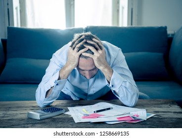 Worried And Desperate Entrepreneur Young Man Calculating Bills Tax Expenses And Counting Business Or Home Finances Sitting On Couch At Home In Paying Off Debts Banking And Financial Problems Concept.