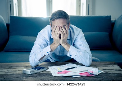 Worried And Desperate Entrepreneur Young Man Calculating Bills Tax Expenses And Counting Business Or Home Finances Sitting On Couch At Home In Paying Off Debts Banking And Financial Problems Concept.