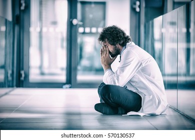 Worried Doctor Sitting On Floor In Hospital