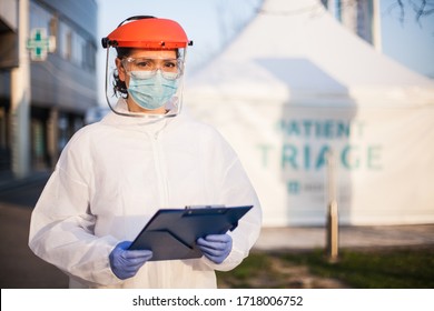 Worried exhausted and stressed frontline UK doctor,wearing PPE and face shield,out of hospital patient triage tent quarantine,special US COVID-19 intensive care unit facility for close contact cases - Shutterstock ID 1718006752