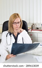 Worried Female Doctor Examining X-ray Of A Patient Suffering From Lung Cancer In Consulting Room