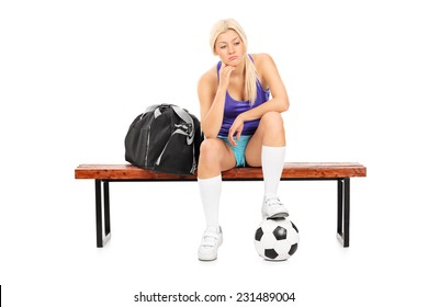 Worried female football player sitting on a bench isolated on white background - Powered by Shutterstock