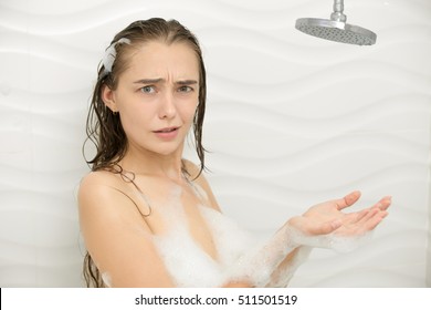 Worried foamed young woman after the water in the shower was turned off, looking at the camera. Lifestyle