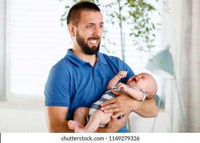 Worried And Frustrated Young Father Holding His Baby Boy Crying.