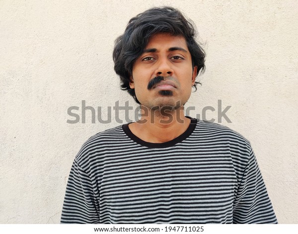 Worried looking South Indian man with half\
shaved moustache. White\
background