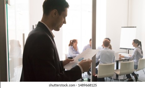 Worried Male Worker Stand Outside Conference Room Reading Paperwork Project Report Get Ready For Presentation, Focused Anxious Man Speaker Prepare Looking Through Paper Notes Before Entering Meeting