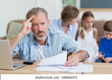 Worried Man Calculating Bills On The Laptop In Living Room At Home