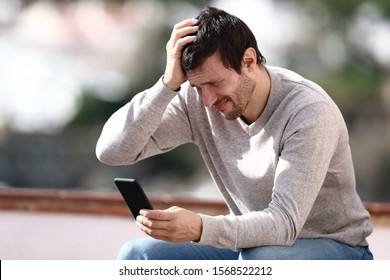 Worried man checking mobile phone complaining after mistake outdoors in a rural town - Shutterstock ID 1568522212