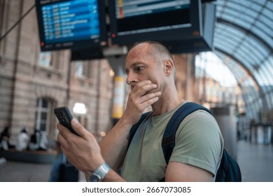 Worried man checking time while waiting for delayed public transport frustrated by train or airplane lateness