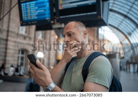 Worried man checking time while waiting for delayed public transport frustrated by train or airplane lateness