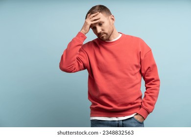 Worried man feeling heartbroken and stress put hand to forehead. Middle aged male isolated on studio blue background with expression of anxiety, detachment, shock, alienation, disappointment on face. 