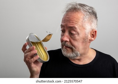 Worried Man Holding And Looking At An Empty Sardine Can