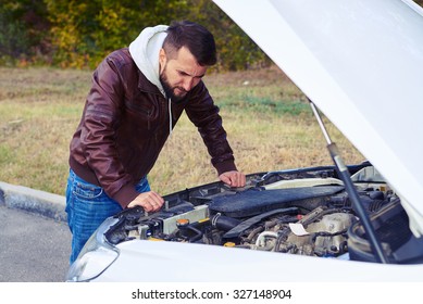 Worried Man Looking Under The Hood Of Breakdown Car At Outdoor