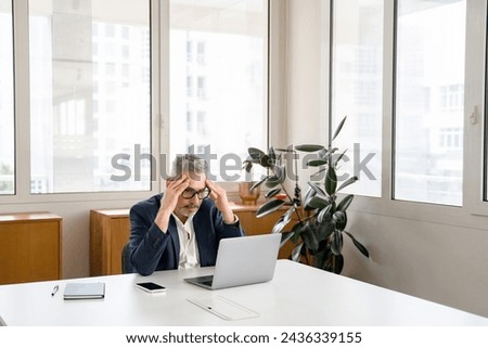 Worried mature male employee colleague staring at laptop screen sitting on the workplace, pensive concerned businessman has problem with project, lack of new ideas, solving problems