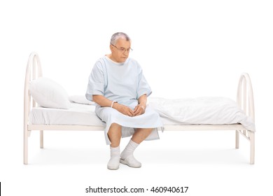 Worried mature patient sitting on a hospital bed and looking at the floor isolated on white background - Powered by Shutterstock
