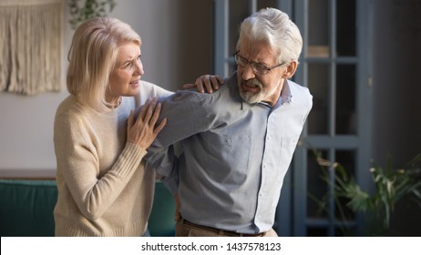 Worried mature wife supporting senior husband feel sudden back pain muscles tension injury at home, upset grandfather touching back having lower lumbago backache, old couple osteoarthritis concept