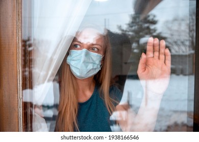 Worried Mid Adult Woman Looking Through Window From Home In Quarantine During Coronavirus. Anxiety Female In Self Distancing Isolation Due To Covid-19.Stay At Home In Time Of Pandemic Concept