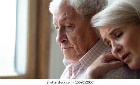 Worried Middle Aged Woman Embracing Upset Old Man From Back, Side View Head Shot Close Up Portrait. Sensitive Mature Wife Showing Support, Comforting Depressed Elder Husband, Experiencing Grief.