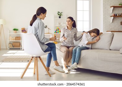 Worried Mother Sitting On Couch With Sad Depressed Kid And Talking To Counseling Therapist. Psychologist And Parent Discuss Ways To Support Unhappy Child With Behaviour Problems And Issues