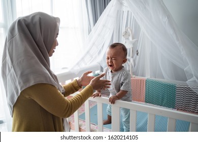 Worried Mother Try To Comfort Her Cry Child At The Crib. Separation Anxiety