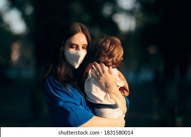 Worried Mother Wearing Face Mask Holding Her Child. Mom Feeling Anxious For The Future During Pandemic Health Crisis
