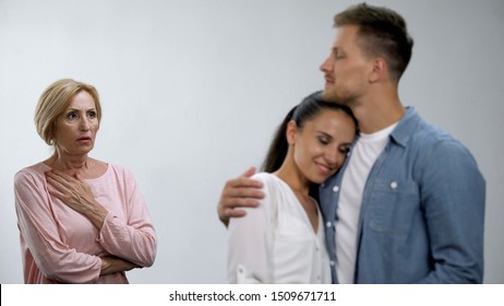 Worried Mother-in-law Looking At Son Hugging Wife, Unwanted Relationship