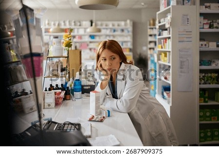 Worried pharmacist thinking of her problems while working in a pharmacy,  