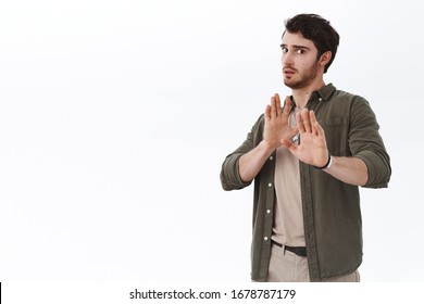 Worried And Scared Young Handsome Man Avoiding Fight. Guy Step Back And Raise Hands In Stop, Refusal Or Defensive Gesture, Turn Away Trying Calm Person Down, Getting Into Trouble, White Background