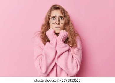 Worried Scared Young Woman Looks Anxious Afraids Of Something Scarying Bites Lips Wears Big Round Spectacles And Warm Cashmere Jumper Isolated Over Pink Background Smells Problems Looks Intense