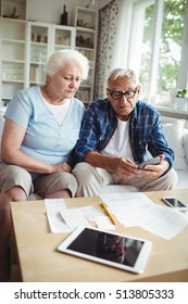 Worried Senior Couple Checking The Bills At Home