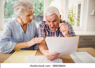 Worried senior couple checking their bills at home