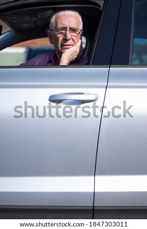 Worried Senior Male Driver Looking Out Of Car Window