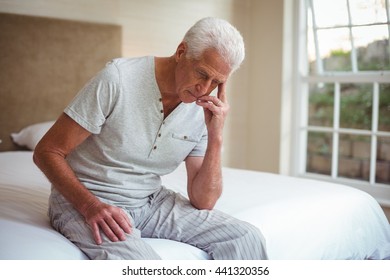 Worried senior man sitting on bed in room - Powered by Shutterstock