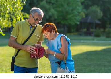 Worried Senior Red Haired Woman And Grey Haired Man Are Looking At An Empty Wallet. Unhappy Bankrupt Woman With Empty Wallet. Mature Woman Shows Her Empty Wallet. Bankruptcy, Stagflation, Inflation