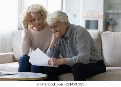 Worried senior wife and husband sit on sofa hold papers with unpleasant news, got notification from bank having financial problems, looking concerned. High taxes, eviction, late payments, subpoenas - Powered by Shutterstock