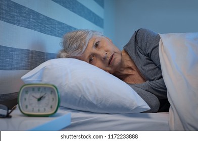 Worried Senior Woman In Bed At Night Suffering From Insomnia. Old Woman Lying In Bed With Open Eyes. Mature Woman Unable To Sleep At Home.