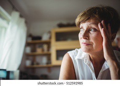 Worried senior woman with hand on forehead at home - Powered by Shutterstock