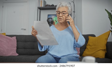 Worried senior woman indoors reading document and talking on phone, expressing concern - Powered by Shutterstock