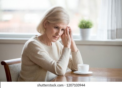 Worried Senior Woman Sitting At Table At Home Lost In Thoughts, Concerned Aged Female Distracted From Reality Thinking About Problems, Sad Elderly Wife Grieve Missing Husband Or Remembering Past