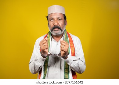 Worried Serious Criminal Politician With Hand Cuffs Looking At Camera On Yellow Background - Concept Of Political Crime, Arrested Political Leader And Trapped In Politics.