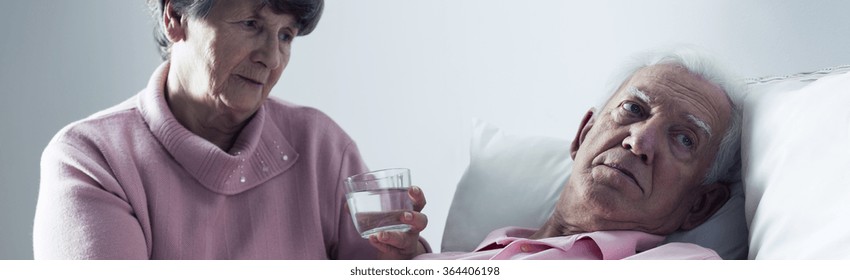 Worried Sick Older Man In Bed And Helpful Wife