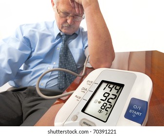 Worried And Stressed Senior Man In Shirt And Tie (businessman Or Teacher) Showing A High Blood Pressure Reading On The Automatic Monitor. On White.