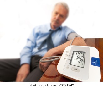 Worried And Stressed Senior Man In Shirt And Tie (businessman Or Teacher) Showing A High Blood Pressure Reading On The Automatic Monitor. On White.